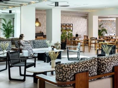 Modern hotel lounge area with wooden furniture and comfortable patterned cushions.