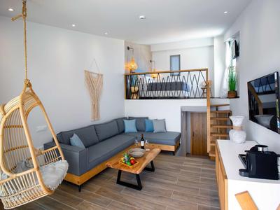 Salon moderne avec canapé d'angle gris, sol en bois et fauteuil suspendu en bois.