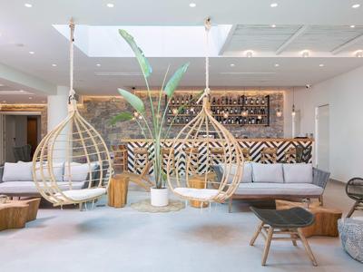 Moderne hotellounge met hangstoelen, houten meubels en gezellige zithoek met sofa.