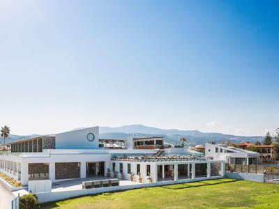 Modern wit hotelgebouw met groot groen gazon voor bergen onder heldere lucht