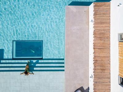 Vue de dessus d'un nageur dans la piscine à côté de chaises longues et d'une terrasse en bois