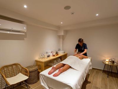 Une salle de massage avec une table de massage, une personne allongée et un masseur.