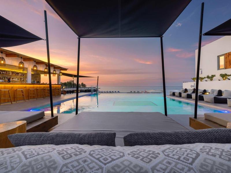 Espace piscine luxueux avec chaises longues et bar au coucher du soleil dans un complexe.