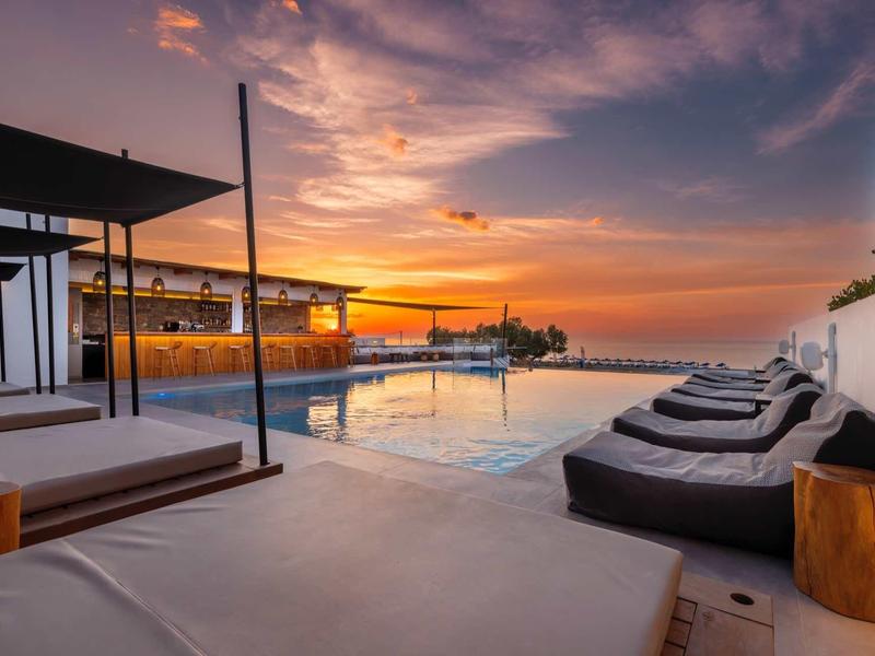 Piscine extérieure moderne avec chaises longues et bar au coucher du soleil dans un hôtel.