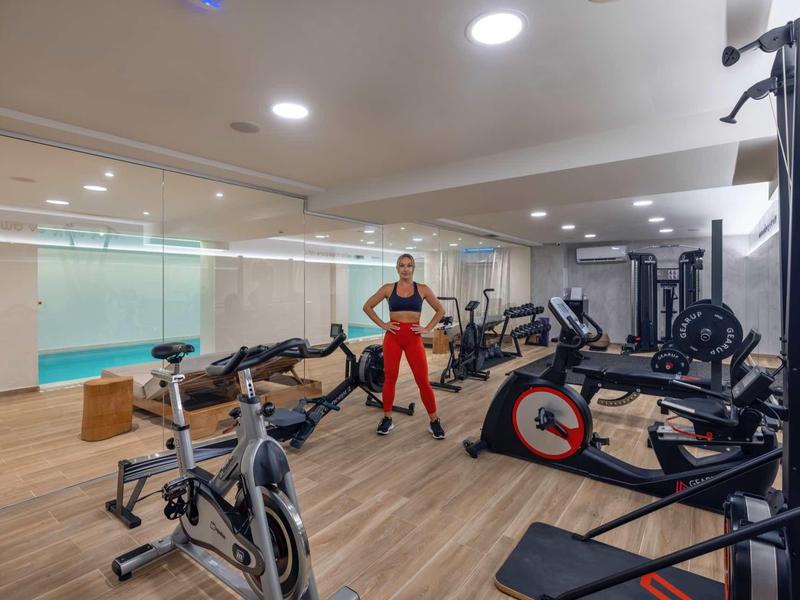 Salle de sport moderne d'hôtel avec équipements cardio et musculation et une personne en tenue de sport.