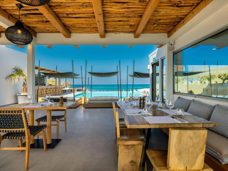 Restaurant ouvert avec plafond en bois et vue sur la mer depuis une terrasse confortable.