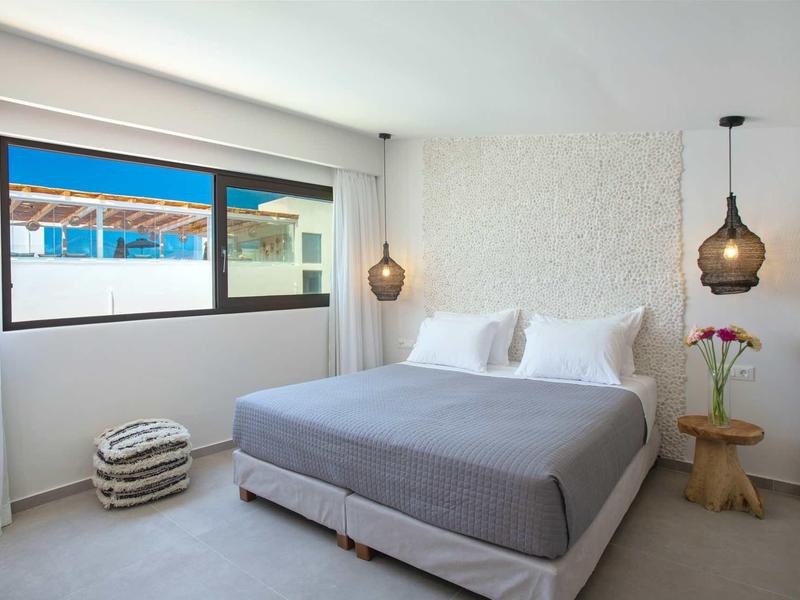 Chambre d'hôtel moderne avec grand lit, éclairage avant-gardiste et vue par la fenêtre.