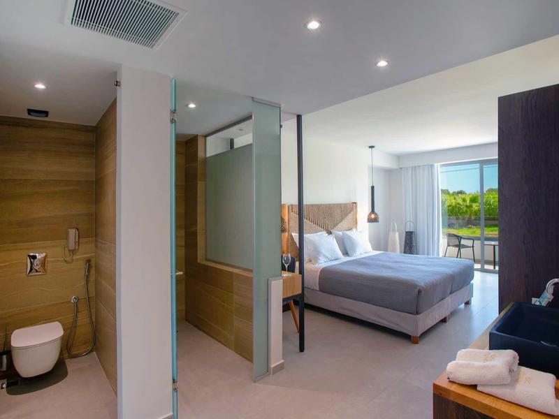 Chambre d'hôtel moderne avec lit double, balcon et salle de bain attenante avec accents en bois.