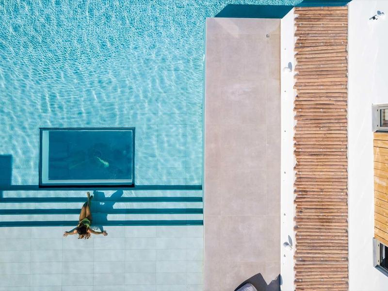 Vue de dessus d'un nageur dans la piscine à côté de chaises longues et d'une terrasse en bois