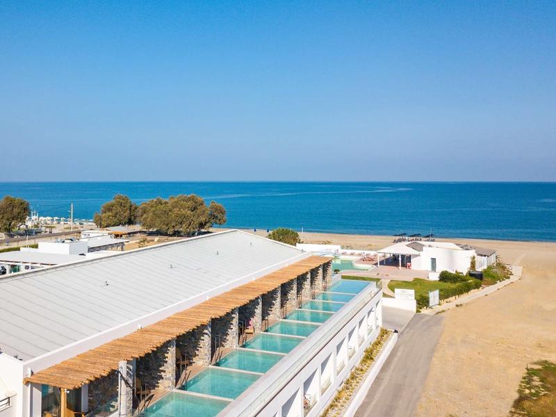 Complexe hôtelier moderne avec une longue piscine donnant sur la plage de sable et la mer