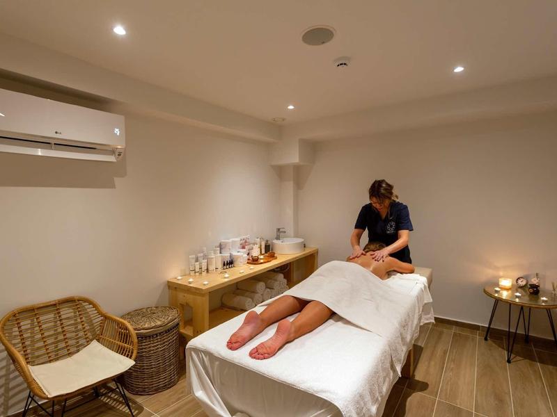 Une salle de massage avec une table de massage, une personne allongée et un masseur.