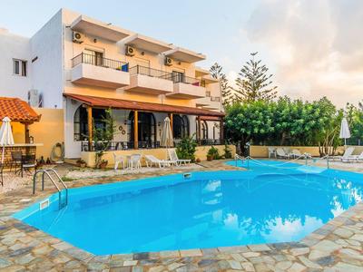 Hotel s venkovním bazénem, lehátky a slunečníky pod modrou oblohou