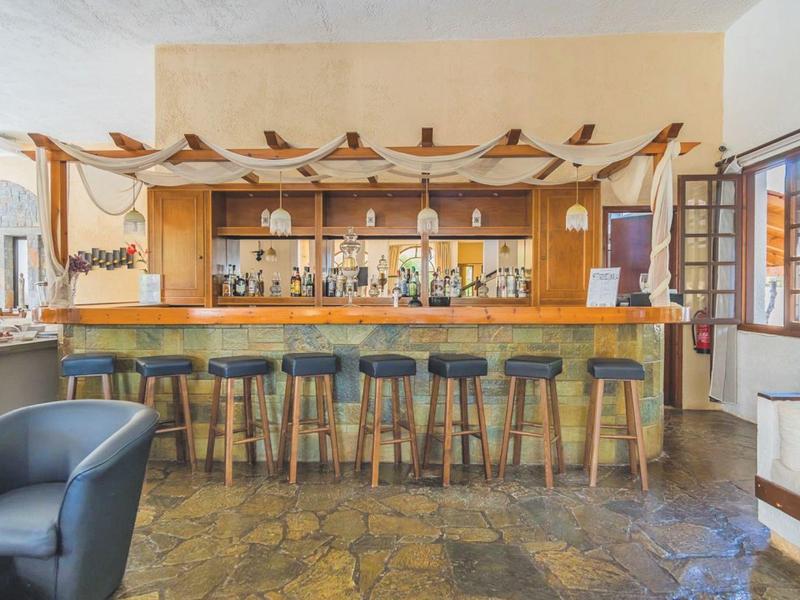 Modern hotel bar with wooden counter, black stools, and large windows