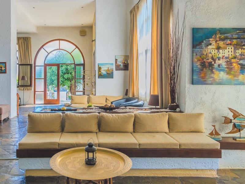 Bright living room with beige sofa, round table, and large window overlooking outdoors.