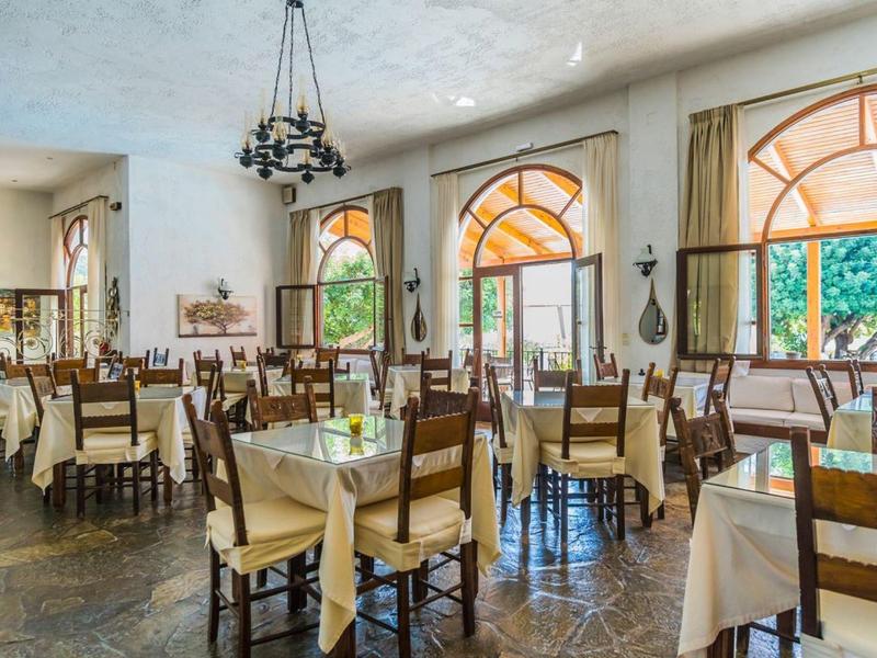 Bright restaurant with wooden furniture and large arched windows letting in daylight.