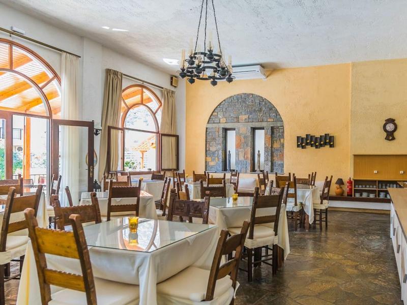 Bright restaurant with wooden tables and chairs, large windows, and yellow walls.