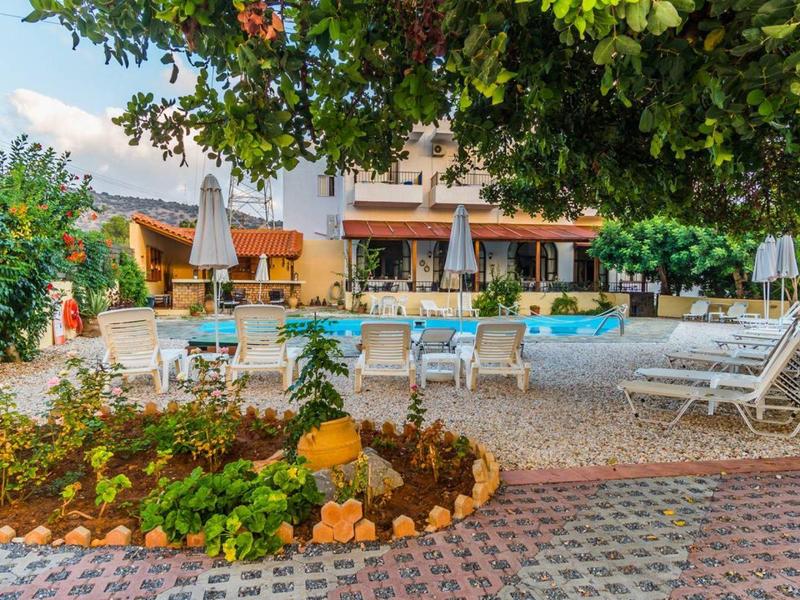 Hotel terrace with seating and pool, surrounded by trees and plants.