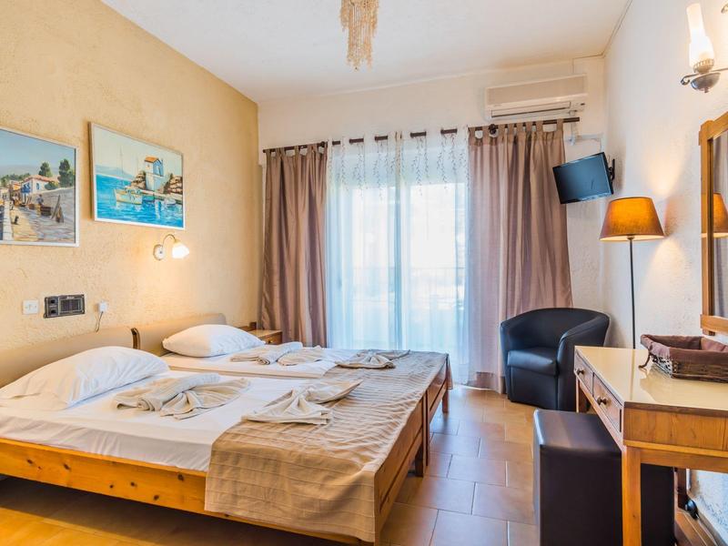 Cozy hotel room with two beds, seating area, and large window with curtains.