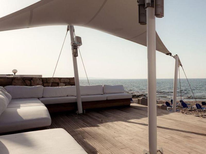 Moderní lounge s bílými pohovkami a slunečními plachtami u moře