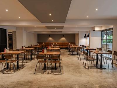 Sala da pranzo moderna e luminosa con tavoli e sedie in legno in un ambiente elegante.