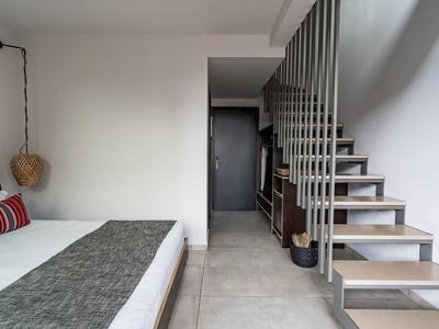 Moderní hotelový pokoj s manželskou postelí a otevřeným schodištěm na zdi.