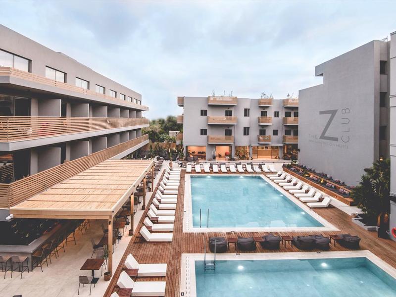 Moderní hotel se dvěma venkovními bazény a lehátky pod polojasnou oblohou.