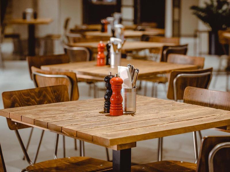 Dřevěné stoly a židle uspořádané v útulné a teplé kavárně.