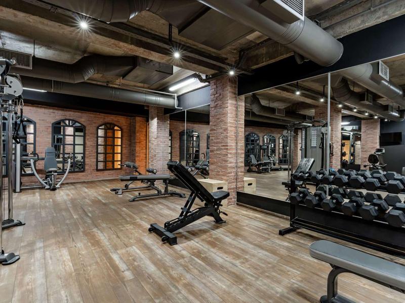 Moderně vybavená posilovna s činkami a stroji v hotelu.