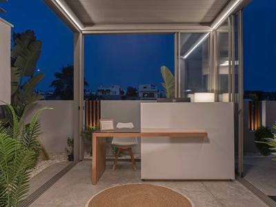 Nowoczesny stół na zewnątrz z krzesłem i roślinami na stylowym, oświetlonym tarasie nocą.