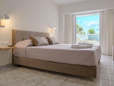 Světý hotelový pokoj s manželskou postelí a balkonem s výhledem na moře.