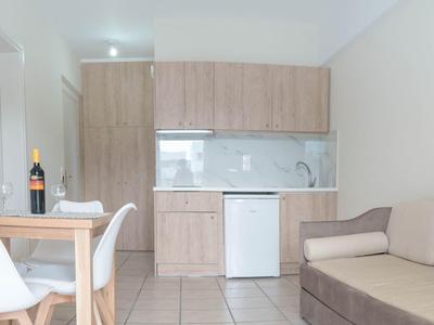 Moderní obývací pokoj s pohovkou, konferenčním stolkem, židlemi a kuchyňským koutem v světlém designu.