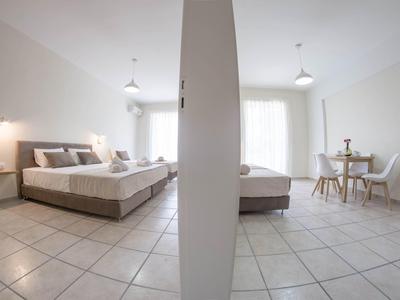 Moderní hotelový pokoj se dvěma postelemi, stolem a židlí, oddělený zdí.