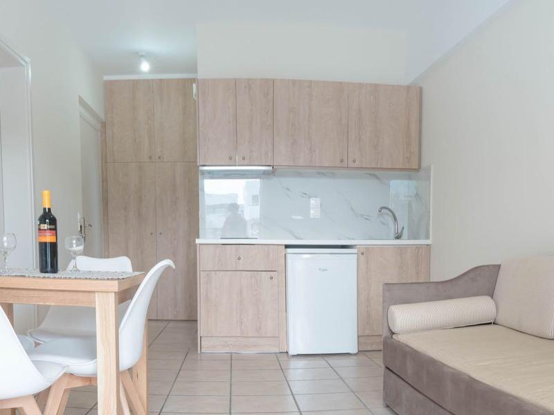 Moderní obývací pokoj s pohovkou, konferenčním stolkem, židlemi a kuchyňským koutem v světlém designu.