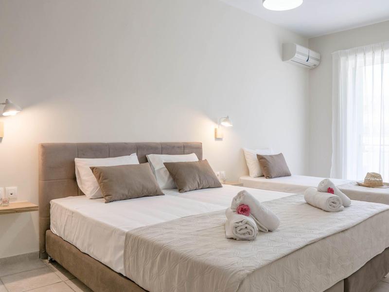 Moderní hotelový pokoj se dvěma jednolůžky, polštáři a pečlivě složenými ručníky.