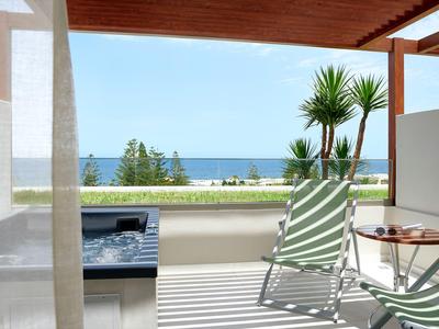 Balkon z leżakami, jacuzzi i widokiem na morze pod czystym niebem.