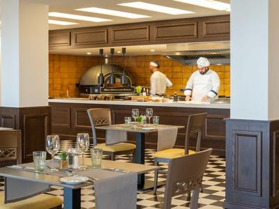 Modernes Restaurant mit gedeckten Tischen und Köchen in der offenen Küche.