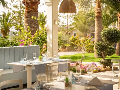 Gemütlicher Außenbereich eines Hotels mit gedeckten Tischen und grüner Gartenanlage.