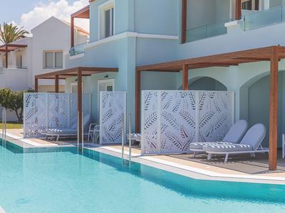 Moderner Hotelpool mit Liegestühlen und Pergolen, umgeben von weißen Gebäuden.