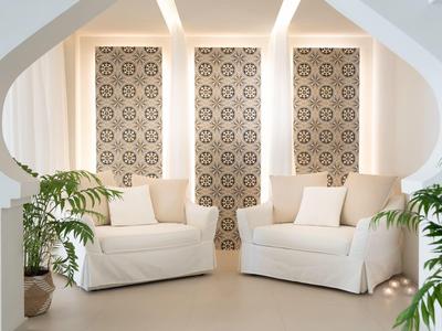 Helles Wohnzimmer mit zwei weißen Sofas, beigen Kissen und dekorativen Fenstervorhängen.