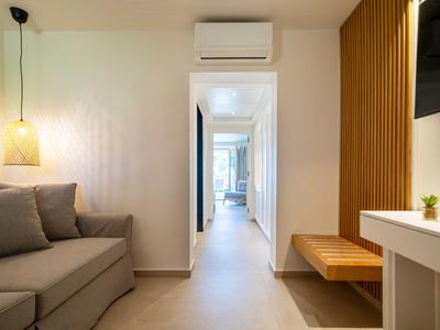 Nowoczesny korytarz z sofą, drewnianymi elementami i białymi ścianami w pokoju hotelowym.