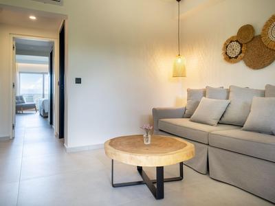 Nowoczesny salon z szarą sofą, okrągłym drewnianym stołem i dekoracją ścienną z drewna dryfującego.