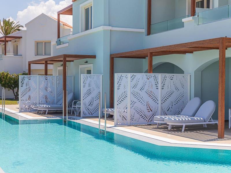 Moderner Pool mit Liegestühlen und blauen, überdachten Sitzbereichen an einem hellen Gebäude.