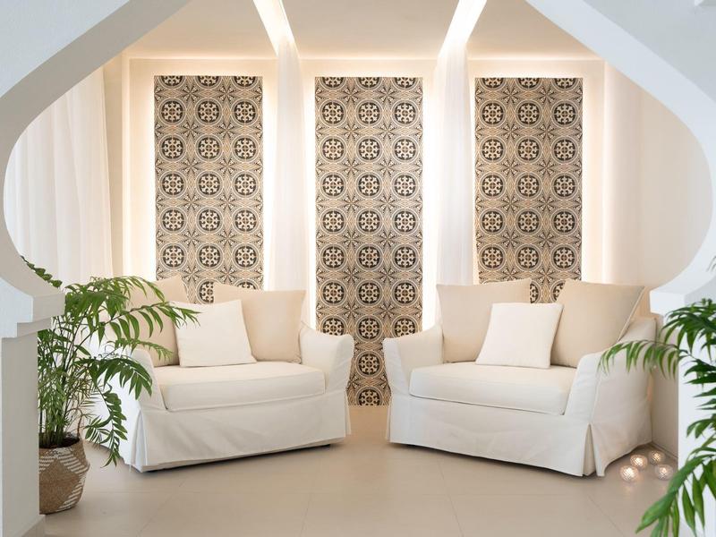 Helles Wohnzimmer mit zwei weißen Sofas, beigen Kissen und dekorativen Fenstervorhängen.