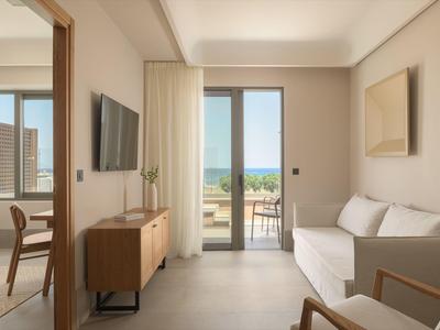 Helle, moderne Wohnung mit weißem Sofa, Holz-Möbeln und großer Glastür zum Balkon mit Meerblick.