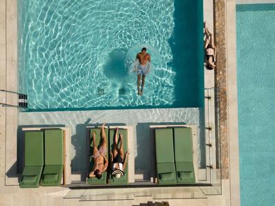 Vue plongeante d'une piscine avec deux transats et trois personnes dans une petite piscine