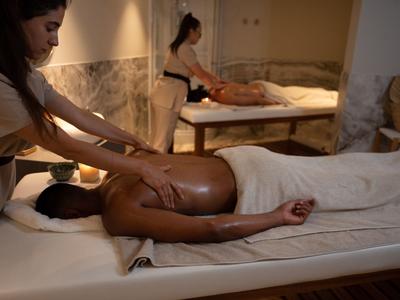 Femme recevant un massage du dos dans une pièce de spa calme et chaleureusement éclairée.
