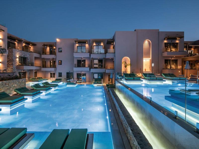 Nowoczesny basen hotelowy oświetlony z leżakami nocą.