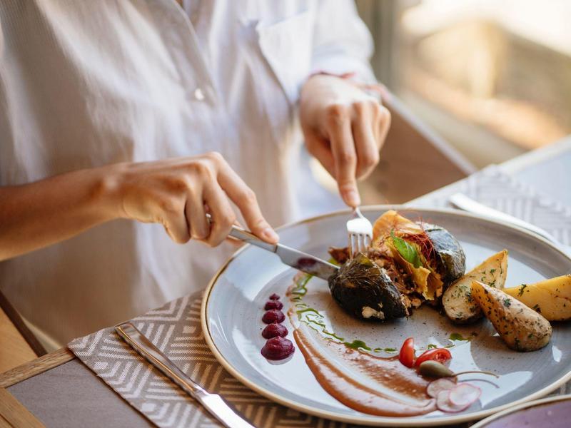 Osoba jedząca elegancki posiłek nożem i widelcem w restauracji.