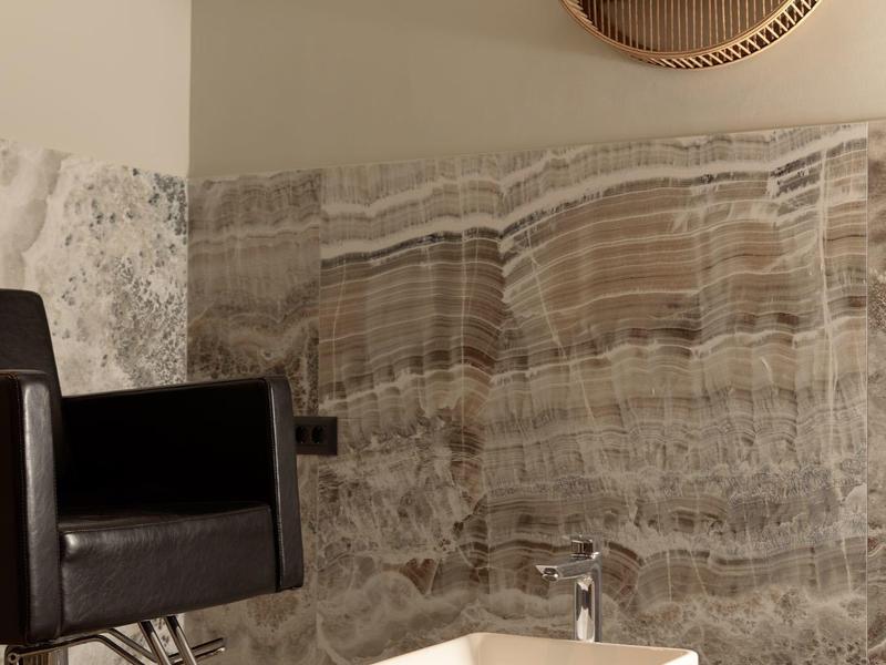 Nowoczesny salon fryzjerski z czarnym fotelem i umywalką z ręcznikiem.