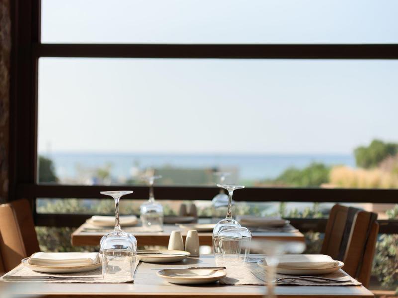 Elegancko nakryty stół z kieliszkami do wina i widokiem na morze w tle.